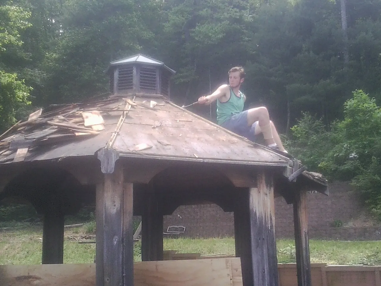 Tearing the old roof off a wooden gazebo before new shakes in Newtonville