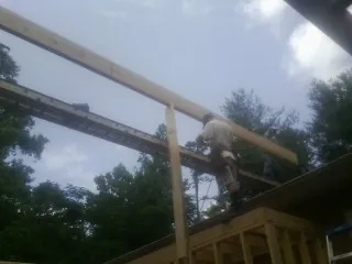 Carpenter setting a ridge beam over a new addition frame — Ice Dam Removal by Roofing Brothers in Newtonville