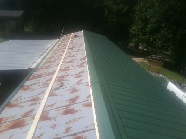 Old rusted panels beside newly installed green metal roofing — Wind Damage Roof Repair by Roofing Brothers in Newtonville