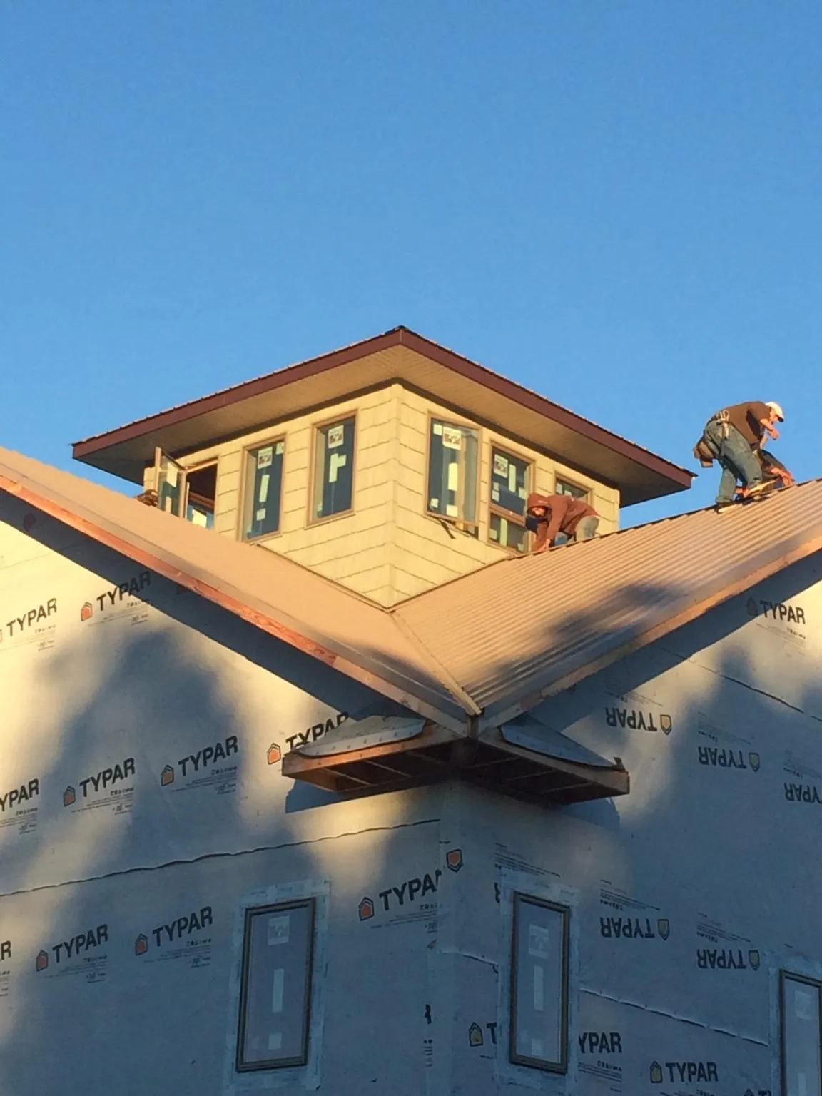 Roofers working around a rooftop cupola on a new metal roof at sunset — Roof Waterproofing in Newtonville by Roofing Brothers